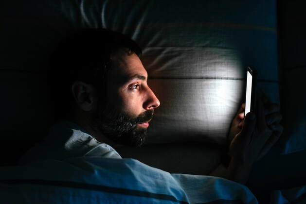 Young man using smartphone in bed Vigo, GA, Spain CR_AIMA210416-697310-01 ,model released, Symbolfoto
