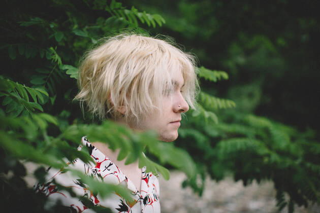 IMAGO Creative: Nächste Generation, Sozial- und klimabewusst Teen Boy With Bleach Blonde Hair Stands in Profile among Green Leaves Nevada City, CA, United States CR_CXBA210422-683370-01 ,model released, Symbolfoto