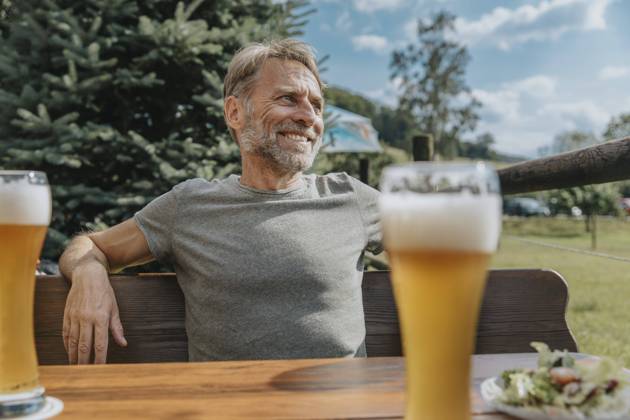 Creative Highlights Symbolbilder Smiling mature man looking away while sitting in beer garden model released Symbolfoto MFF07644