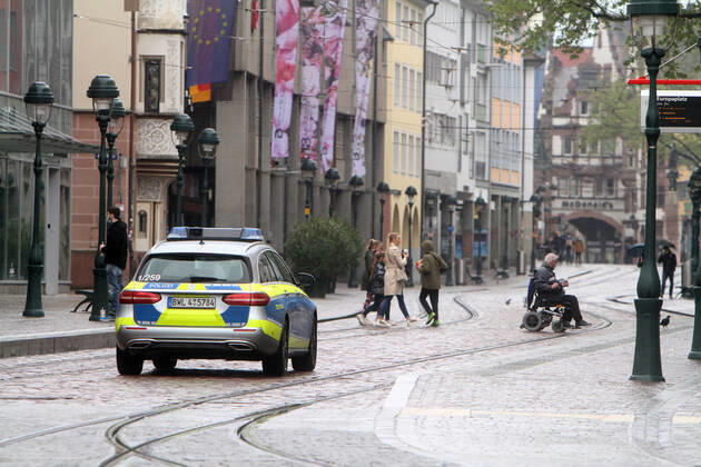 A police patrol of the state police of Baden Württemberg drives through the almost deserted pedestrian zone and shopping street Kaiser Joseph Straße in the city center of Freiburg, Baden Württemberg, Bavaria, Germany.