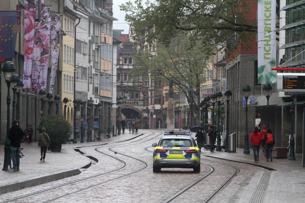 A police patrol of the state police of Baden Württemberg drives through the almost deserted pedestrian zone and shopping street Kaiser Joseph Straße in the city center of Freiburg, Baden Württemberg, Bavaria, Germany.