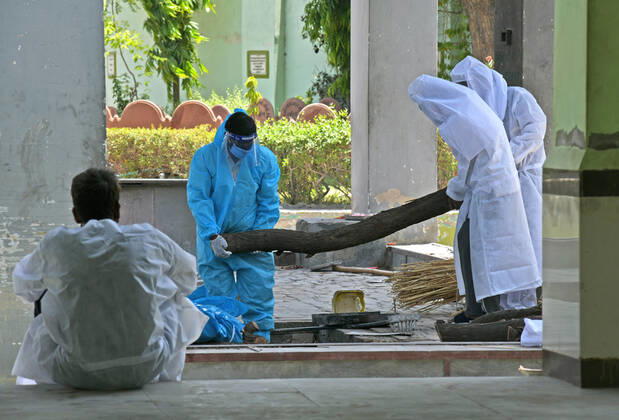 Cremation Of COVID-19 Victims In Rajasthan, India Family members, wearing protective suits, prepare wooden pyre for cremation of COVID-19 victim at Hindu Moksha Dham crematorium in Beawar. Beawar Rajasthan India Copyright: SumitxSaraswat