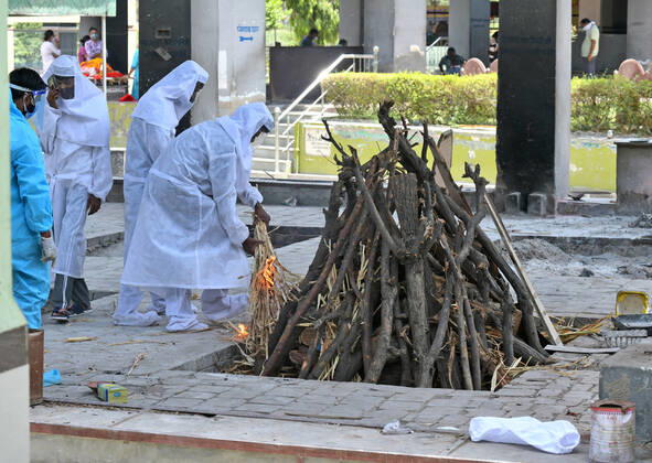Cremation Of COVID-19 Victims In Rajasthan, India Family members, wearing protective suits, perform last rites before cremation of COVID-19 victim at Hindu Moksha Dham crematorium in Beawar. Beawar Rajasthan India Copyright: SumitxSaraswat