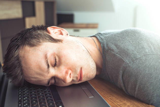 Bavaria, Germany - 18 May 2021: tired man sleeps on his notebook at work in home office - he lies with head on keyboard