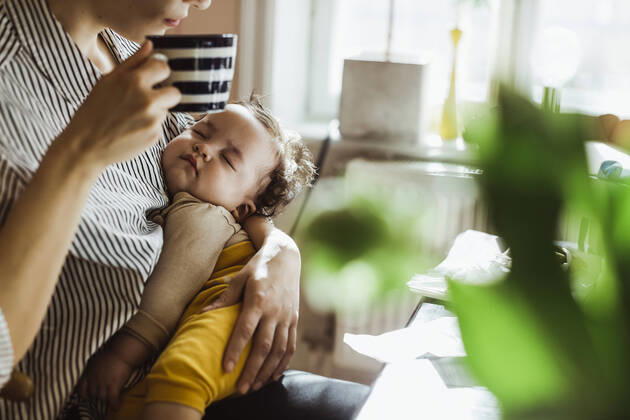 Midsection of mother drinking coffee while carrying sleeping baby boy at home Sweden, Stockholm, model released, property released Copyright: xMaskotx , MA86900