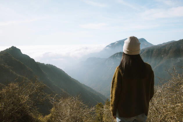 Back view of unrecognizable woman in warm clothes standing alone on viewpoint and looking at foggy mountain ridges covered fluffy clouds in Sequoia National Park under blue sky in USA, Model released Copyright: xLeirexUnzuetax MR