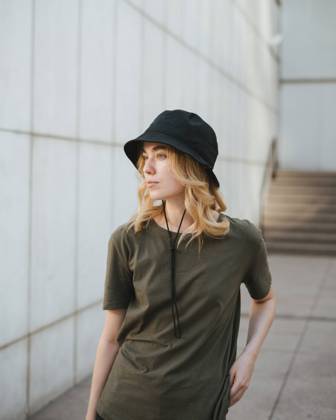 Young female in casual apparel looking away against concrete wall of modern building on urban pavement in daytime Copyright: xMiguelxPalomox Model Released