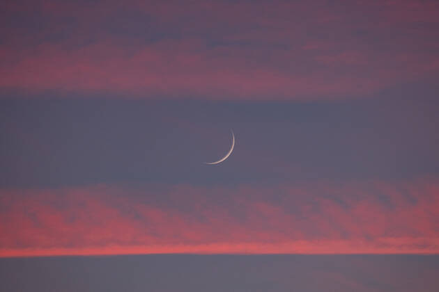 Two days old new moon in the sky over Aachen against a background of pink clouds that owe their color to the sunset. In Aachen on June 12, 2021 GERMANY - AACHEN - WEATHER