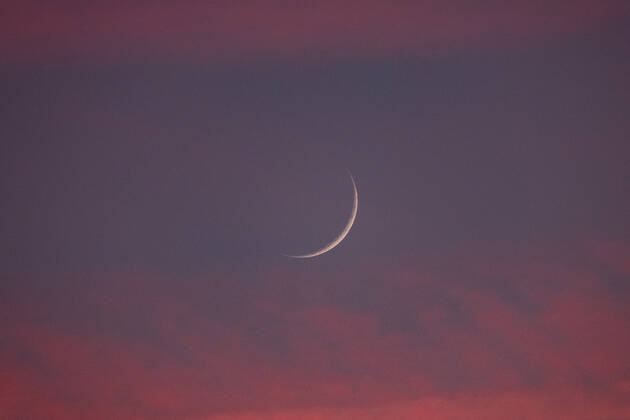 Two days old new moon in the sky over Aachen against a background of pink clouds that owe their color to the sunset. In Aachen on June 12, 2021 GERMANY - AACHEN - WEATHER