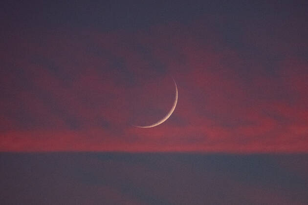 Two days old new moon in the sky over Aachen against a background of pink clouds that owe their color to the sunset. In Aachen on June 12, 2021 GERMANY - AACHEN - WEATHER