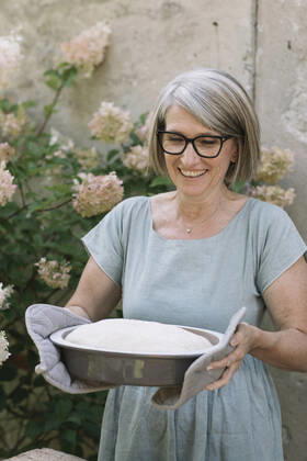 Excited woman carrying baked bread pan at back yard model released Symbolfoto property released ALBF01616