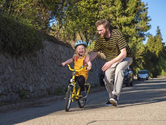 IMAGO Creative: Vaterschaft Father supporting daughter while cycling on road model released Symbolfoto LAF02713