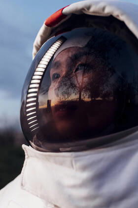 IMAGO Creative: 2022 Aussichten Female astronaut looking away with reflection of illuminated light on helmet during sunset model released Symbolfoto property released MEUF02500