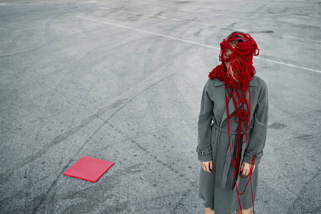 Woman covering face with thread while standing by red placard on road model released Symbolfoto RCPF00996