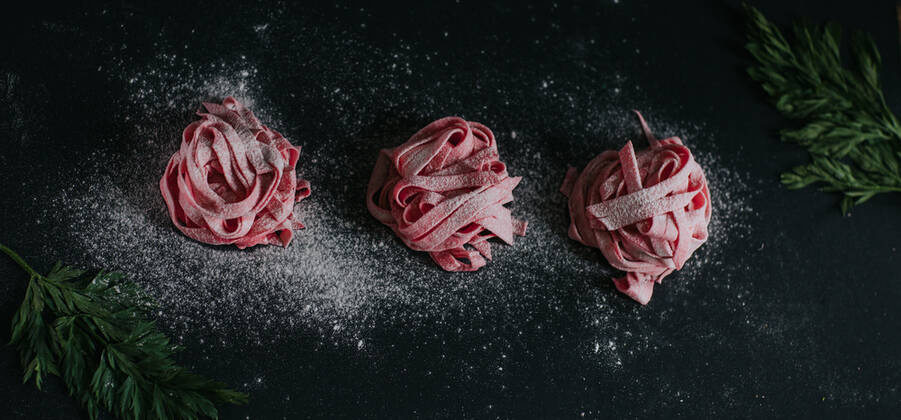 Appetizing vegan beetroot pasta of pink color served on black table in studio Copyright: xCamillexGirardx Model Released