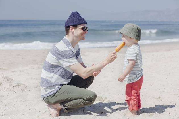Smiling man feeding ice cream to son at beach during sunny day model released Symbolfoto ACTF00062