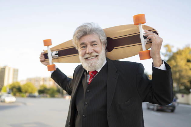 Smiling businessman carrying skateboard in city model released Symbolfoto JCCMF02620