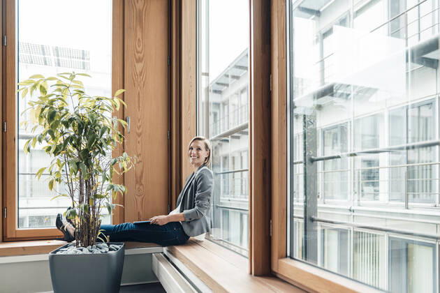 Female entrepreneur smiling while sitting by window model released Symbolfoto property released JOSEF04784