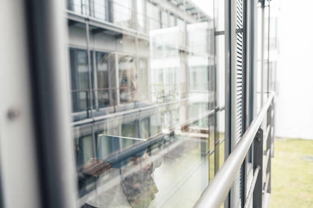 Businesswoman with digital tablet looking through office window model released Symbolfoto property released JOSEF04792