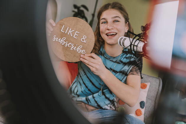 Girl showing like and subscribe sign while vlogging at home model released Symbolfoto property released MFF08035