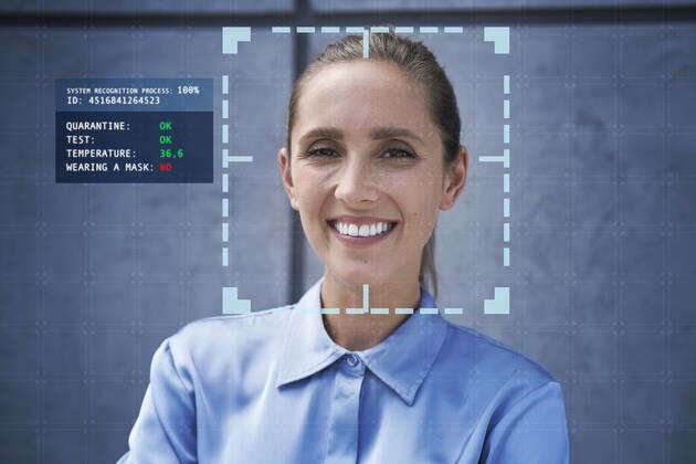 Smiling businesswoman with facial recognition technology in front of wall model released Symbolfoto property released ABIF01402