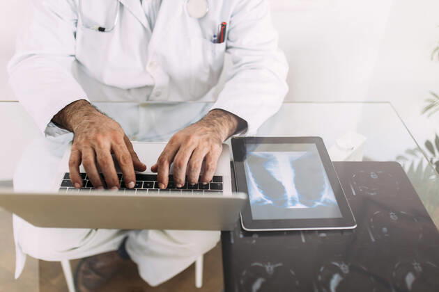 Senior male doctor working on laptop at desk in clinic model released Symbolfoto property released EGHF00042