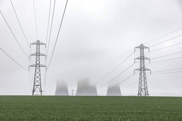 UK, England, Rugeley, Electricity pylons standing in field during foggy weather with cooling towers in background WPEF04930