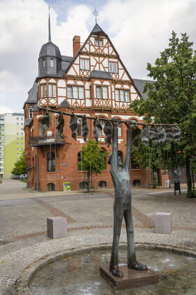 The tobacco fountain by the artist Jan Witte Kropius on the Vierradener Platz in Schwedt Oder district of Uckermark The fountain shows a worker hanging tobacco to dry A little devil leans against a seat and smokes a pipe Photo Volker Hohlfeld The tobacco fountain in Schwedt Oder