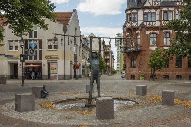 The tobacco fountain by the artist Jan Witte Kropius on the Vierradener Platz in Schwedt Oder district of Uckermark The fountain shows a worker hanging tobacco to dry A little devil leans against a seat and smokes a pipe Photo Volker Hohlfeld The tobacco fountain in Schwedt Oder