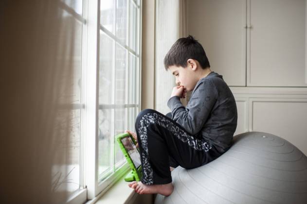 Boy 9-10 years old sits on exercise ball playing with his tablet Grimes, IA, United States CR_LIPF210212B-629689-01 ,model released, Symbolfoto