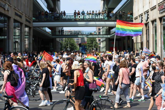 Berliner CHRISTOPHER STREET DAY 2021 - CSD - Am 24. Juli 2021 zieht der CSD in Berlin unter dem Motto SAVE OUR COMMUNITY SAVE YOUR PRIDE zum 43. Mal durch die Hauptstadt. Demozug bewegt sich am Shopping-Center MALL OF BERLIN vorbei. In der Mitte weht die Regenbogenfahne eines Demoteilnehmers. Die bunte CSD-Parade startete in diesem Jahr als Demonstration an der Leipziger Straße, führte über den Potsdamer Platz, vorbei am Denkmal für die im Nationalsozialismus verfolgten Homosexuellen zum Brandenburger Tor und über die Siegessäule zur Urania. Aufgrund der Corona-Pandemie fand die Demonstration ausschließlich unter Einhaltung der vom Berliner Senat erlassenen Vorgaben statt. Die in den Vorjahren übliche Abschlusskundgebung musste