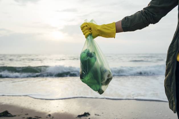 Creative Highlights Symbolbilder Mid adult woman holding garbage bag while standing at beach model released Symbolfoto OYF00248
