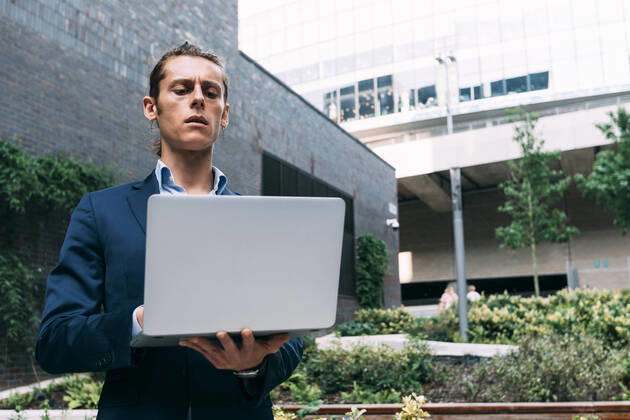 IMAGO Creative: Klimawandel - Zukunft und Innovation Businessman using laptop while standing in park model released Symbolfoto ASGF00815