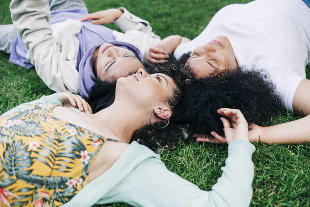Young male and female friends lying on grass at park model released Symbolfoto ASGF00877