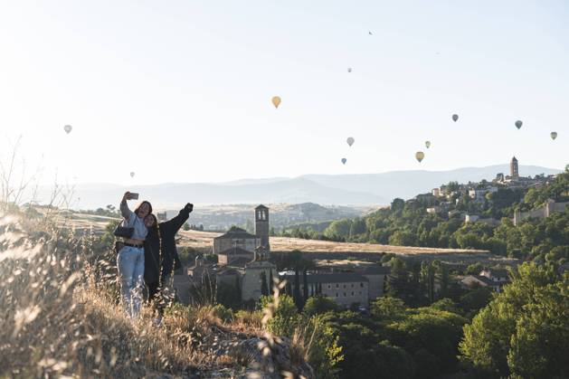 IMAGO Creative, Jahreszeit Sommer, Sommer in der Stadt Spain, Castile and Leon, Segovia, Two sisters taking selfie with flying hot air balloons and historical city buildings model released Symbolfoto JAQF00693