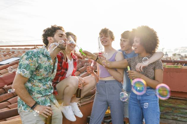 Cheerful young male and female friends blowing bubbles together on rooftop model released Symbolfoto property released IFRF01022