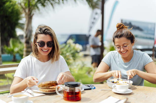 Young female friends having breakfast at table during vacation model released Symbolfoto PGF00740