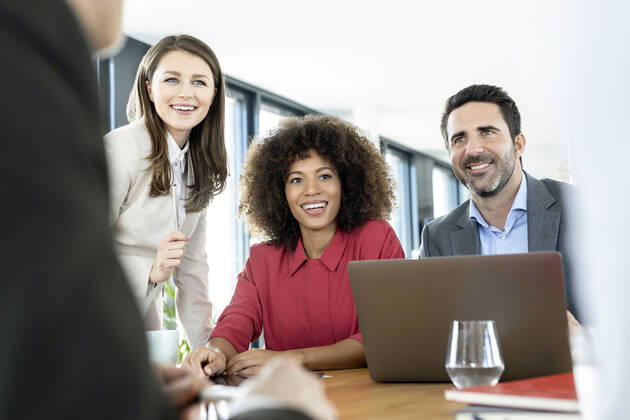 Smiling colleagues with laptop attending meeting at office model released Symbolfoto property released PESF03002