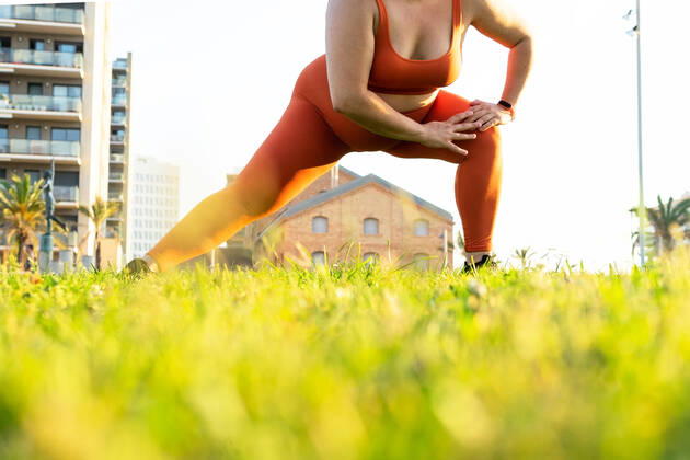 IMAGO Creative, Jahreszeit Sommer, Sommer in der Stadt Ground level of crop anonymous plump female athlete working out on lawn against urban buildings in sunlight DavidMunoz_MontseSport_43.jpg Copyright: xDavidxMunozx Model Released