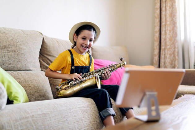 Mindful child with saxophone and with a tablet on couch, Model released SergioVictorVega_SaxoBeat_11.jpg Copyright: xSergioxVictorxVegax MR