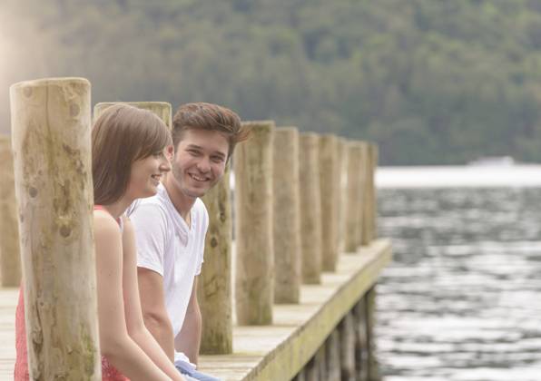 IMAGO Creative, Jahreszeit Sommer, Sommerferien Young couple laughing together on jetty over lake, 06.10.2014, Copyright: xJonathanxMarkxOgdenx, model released, wearing,playing,flirting,differential focus,escape,calm,carefree,exhilaration,freedom,fun,romance,serene people,togetherness,tranquil,shyness,friendship,happiness,joy,love,getting away from it all,young love,teenager,16 to 17 years,only teenagers,female,teenage girl,male,teenage boy,couple,heterosexual couple,two people,united kingdom,cumbria,outdoors,lake windermere,summer,day,pier,casual clothing,t-shirt,laughing,sitting,smiling,water,leisure,edge,relationship,teenage couple,coy,October 2014 Release,Playing,Sitting,Flirting,Teenager,Late Teens,16-17 Years,Female,Girls,Teenage Girls,Teenage Girl,Male,Boys,Teenage Boys,Teenage Ref:IS09AL1XH
