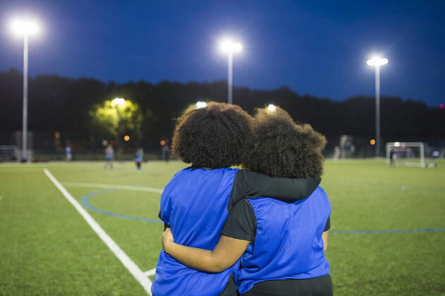 IMAGO Creative: Internationaler Frauenmonat, Mädchen im Sport Female football players sitting by field, Hackney, East London, UK, 12.10.2017, Copyright: xBenxPipexPhotographyx, model released, wearing,practising,focus on foreground,rear view,waist up,girl power,connections,real people,achievement,athleticism,bonding,fitness,teamwork,friendship,floodlight,16 to 17 years,mixed race ethnicity,female,girl,teenage girl,woman,two people,soccer player,people in the background,unrecognizable person,united kingdom,london,outdoors,night,soccer pitch,soccer uniform,communication,hand on shoulder,sitting,afro,leisure,sport,soccer,active lifestyle,empowered,african ethnicity,relationship,field,only female,hackney,sports bib,October 2017 Release,Practising,Hand On Shoulder,Sitting,African Descent,Mixed Race Pers Ref:IS09B8U0I