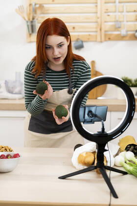 Woman filming through mobile phone while standing in kitchen model released Symbolfoto property released GIOF13210
