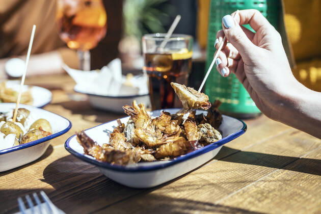 IMAGO Creative, Food, Tapas Woman having fried prawn in restaurant model released Symbolfoto property released JSRF01578