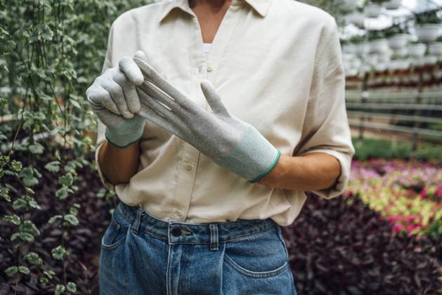 IMAGO Creative, Frühling, Start der Garten-Saison Creative Highlights Symbolbilder IMAGO Creative: Klimawandel - Zukunft und Innovation Female agriculture worker removing protective glove while standing in plant nursery model released Symbolfoto property released VPIF04702