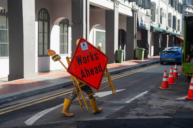 23 09 2021, Singapore, Republic of Singapore, Asia A worker in the city center carries a device with a street sign and warning light during the ongoing Corona crisis.