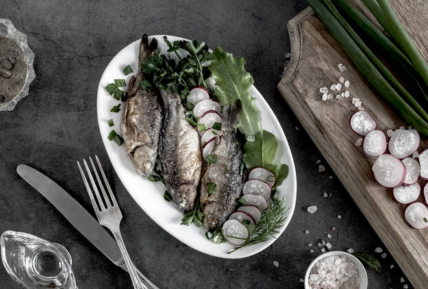 IMAGO Creative, Food, Karpfen-Saison Fried crucian carp on a plate with vegetables On the plate are fried crucian carp, radishes , green onions and lettuce. Top view, close-up. Copyright: xx 37265290