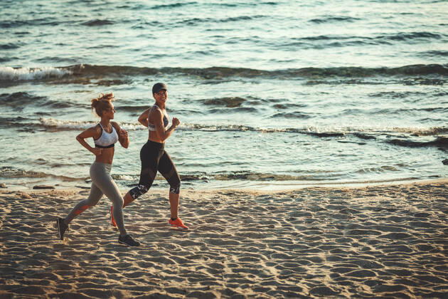 IMAGO Creative: Sommer Sport - Strand Freedom Two smiling happy young women are running along the sea shore on the beach during the hot summer vacation day. Copyright: xMilanxMarkovicx 39002194