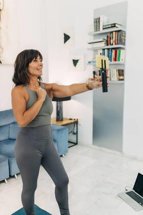 Female vlogger in sports clothing filming video though mobile phone while vlogging at home model released Symbolfoto property released JRVF01878