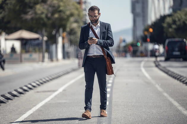 Male business professional using mobile phone while walking in city model released Symbolfoto JSRF01648